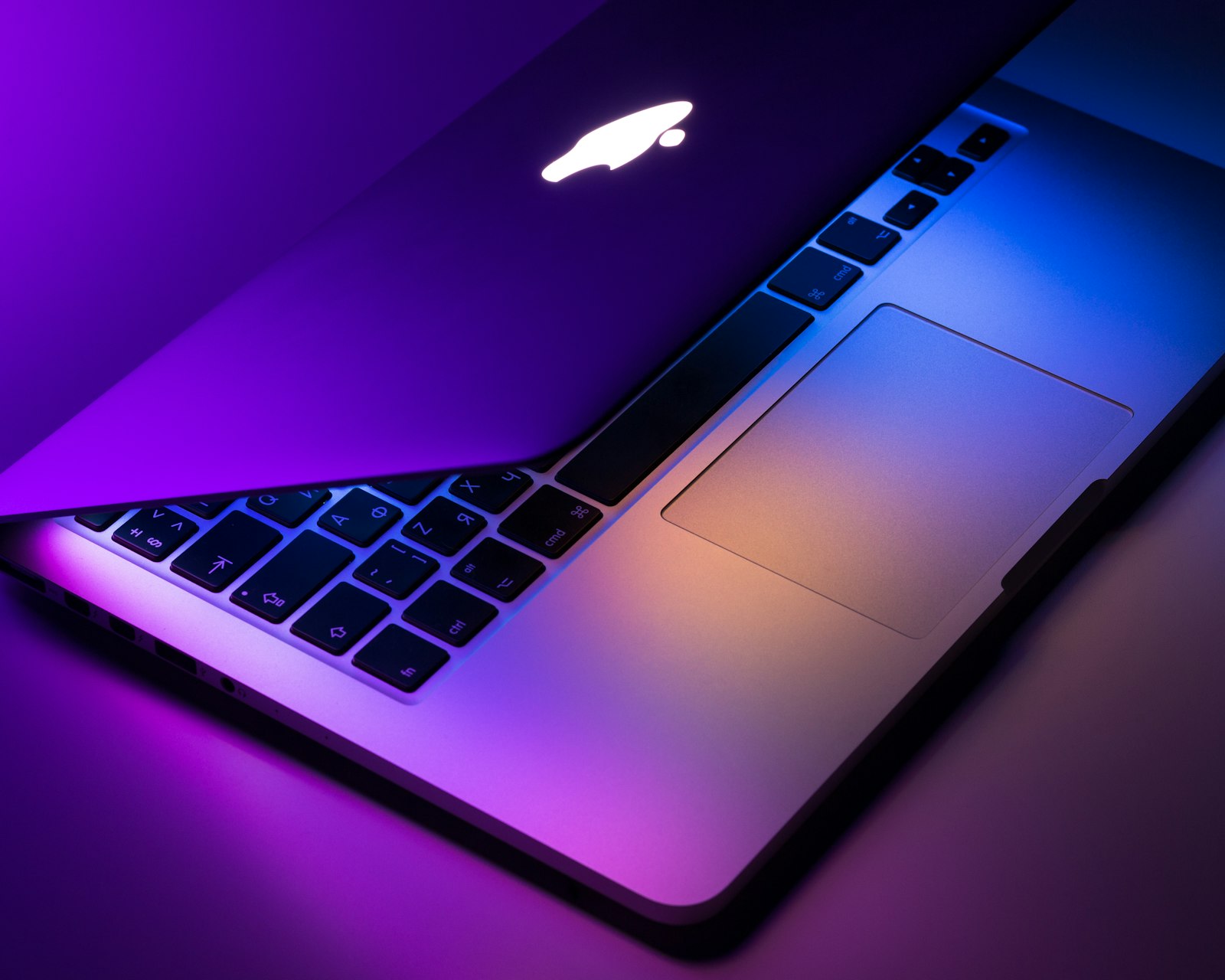 MacBook deschis, cu lumină violet și albastră